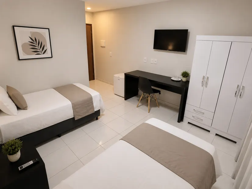 Quarto duplo da Pousada Itaretama com duas camas, Smart TV, mesa de trabalho, armário e frigobar